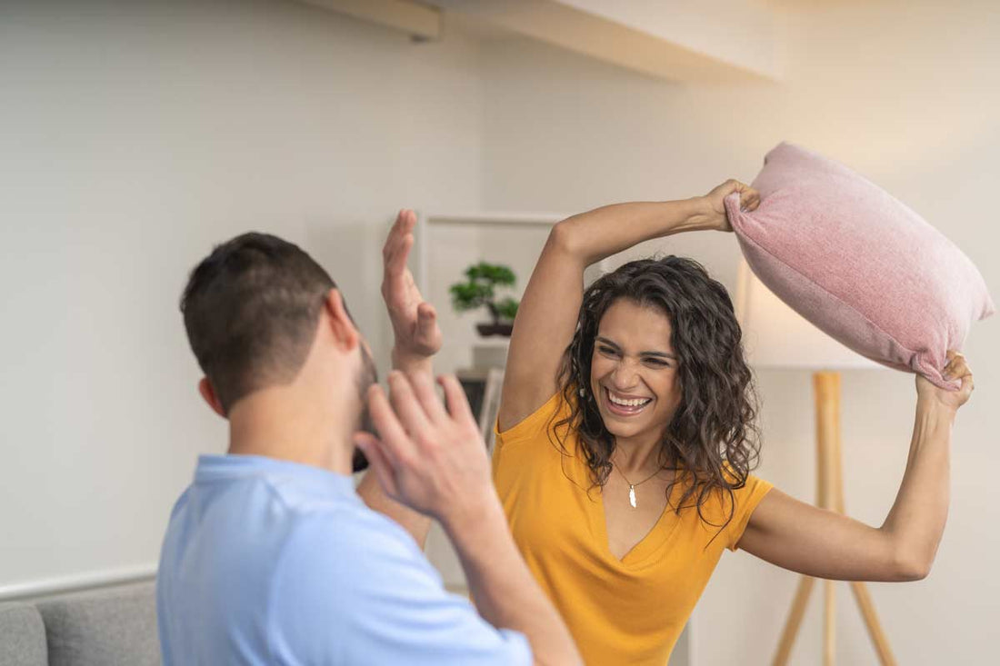 happy couple playing with pillow at home